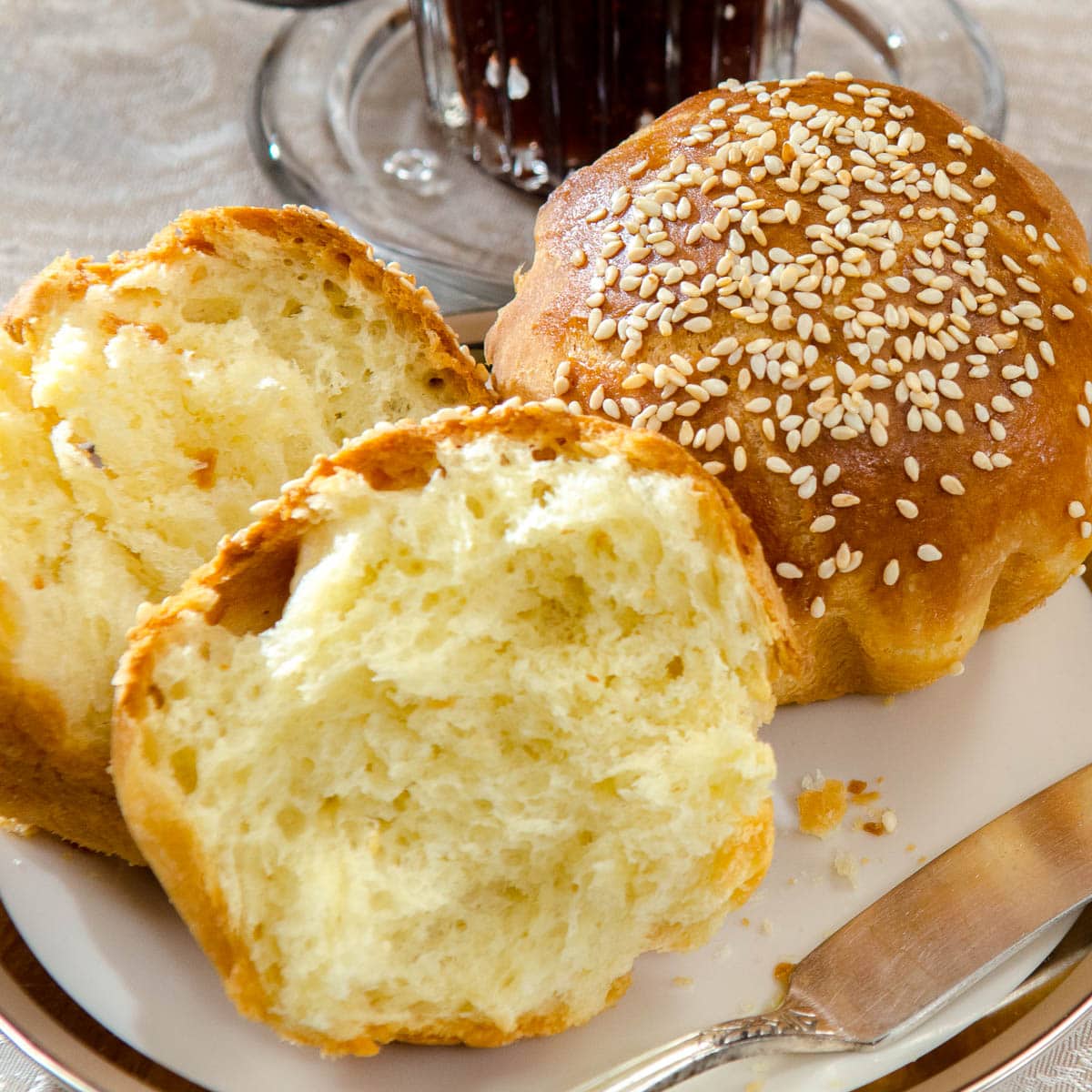 Two Brioche Rolls are on a plate with a jar of jam.