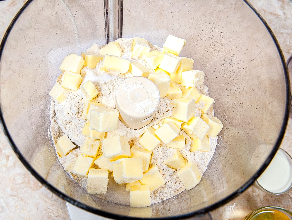 Cold, cubed butter is placed over the flour mixture in the processo.