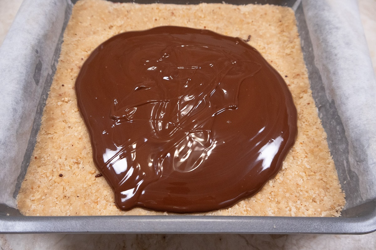 The glaze for the No Bake Cookie Bar is poured over the top layer in the pan.