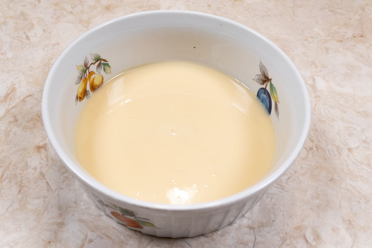 A 12 ounce can of sweetened condense milk is poured into an ovenproof bowl.