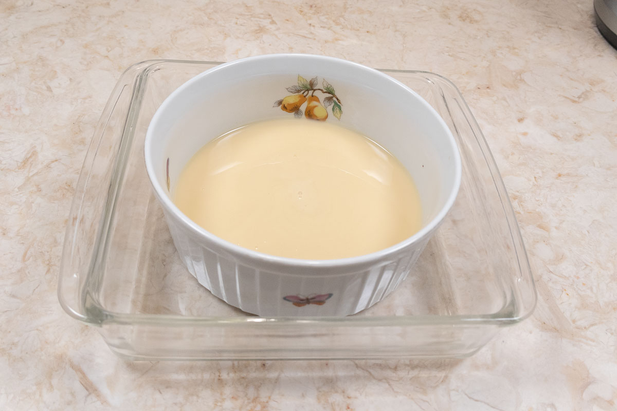 The bowl of condensed milk is placed in a larger oven proof container in order to water bath it.