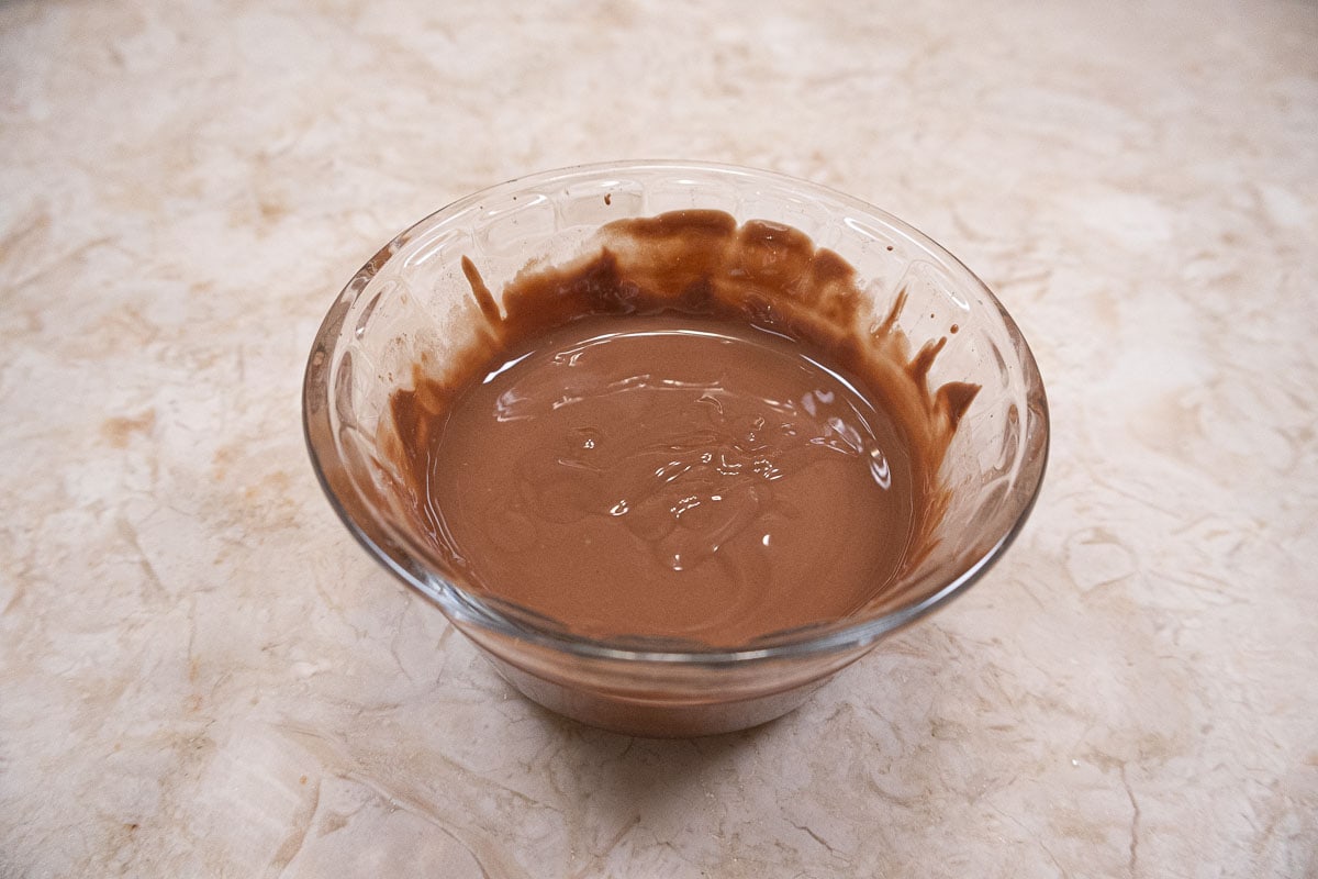 Milk chocolate and shortening are melted in a small bowl.