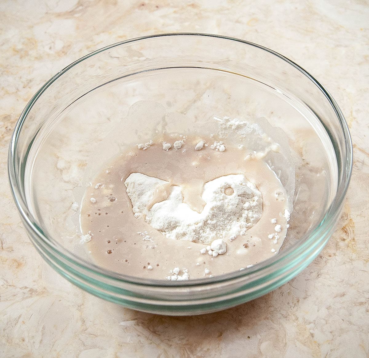 The 2 tablespoons of flour are combined in a bowl with the yeast, water and a pinch of sugar.