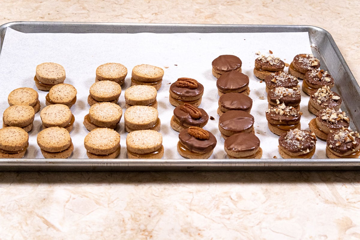 Tray of cookies finished with a pecan on top, pecan sugar, plain chocolate, plain cookies or topped with sanding sugar.