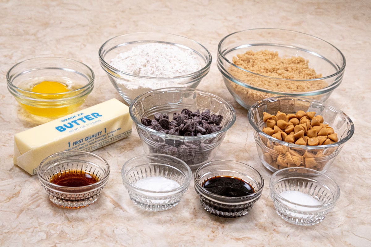 Ingredients for the chocolate butterscotch chip topping include back row: egg, flour, brown sugar,middle row: butter, chocolate and butterscotch chips, front row, vanilla, baking soda, molasses, salt
