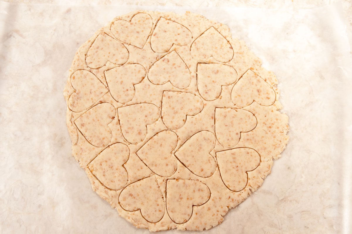 Heart shaped cookies cut out of the dough closely together.