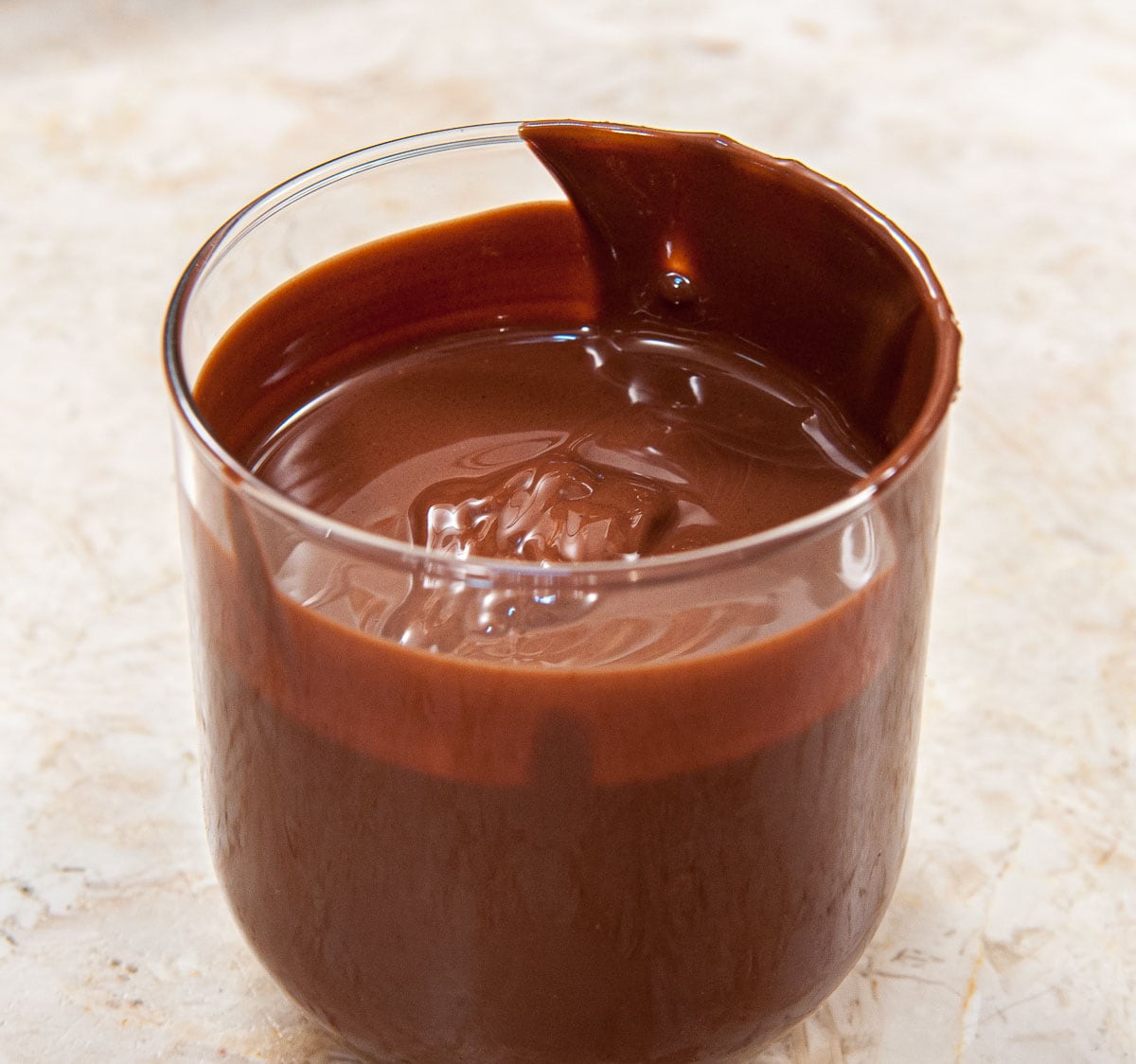 The melted chocolate  has been poured into a narrow glass to facilitate dipping.