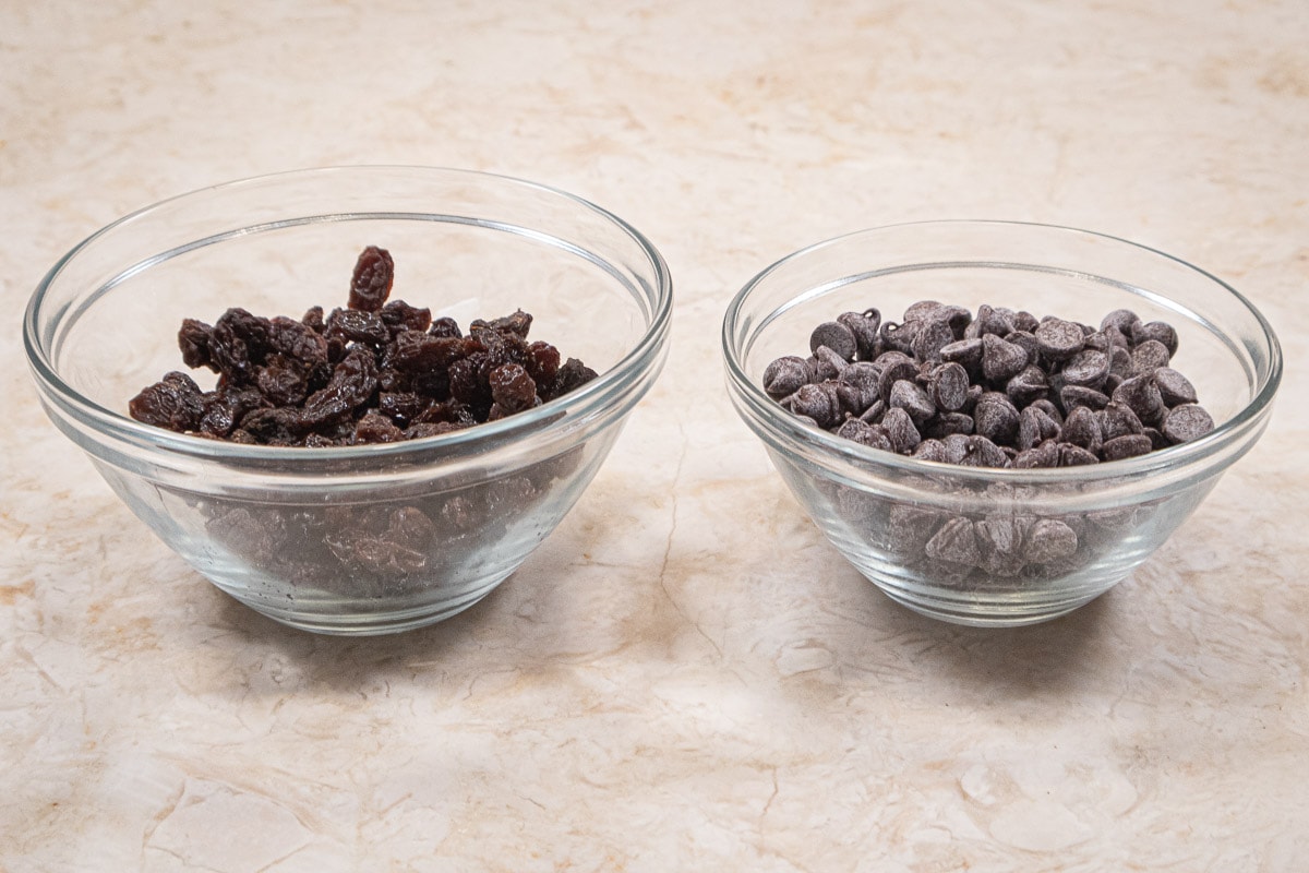 Bowls of raisins and chocolate chips to be added to the basic muffin mix.