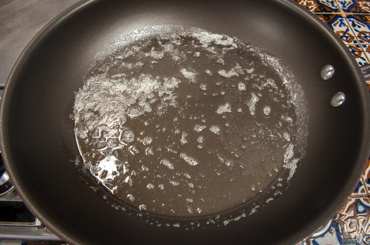 Butter is melted in a dark saute pan awaiting the dipped French toast.