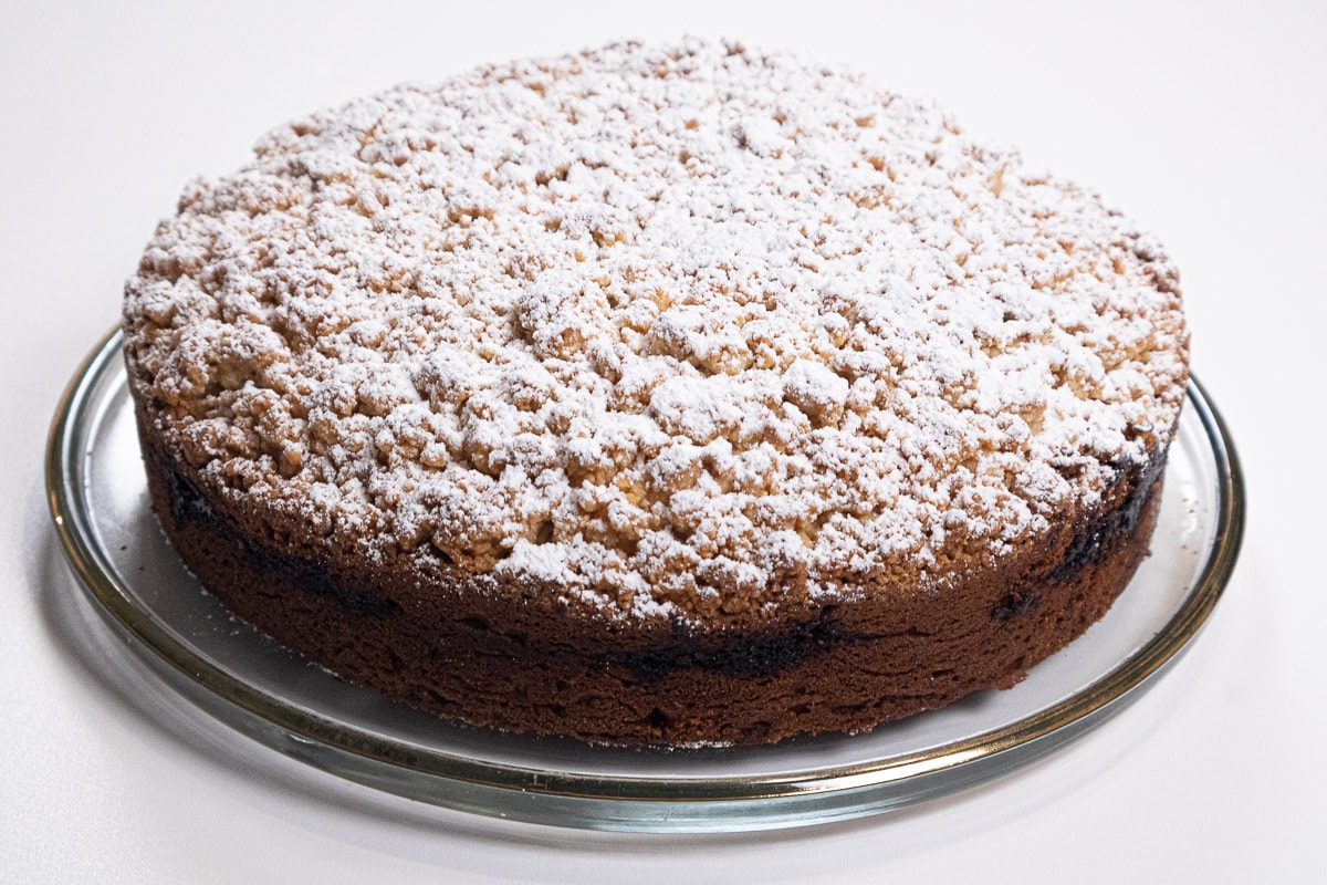 Whole coffee-cake dusted with powedered sugar on a serving tray.