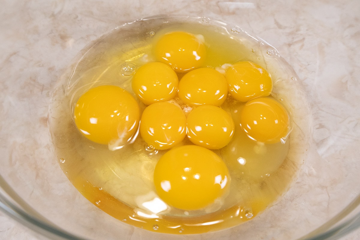 The whole eggs and egg yolks are placed in a large bowl. 