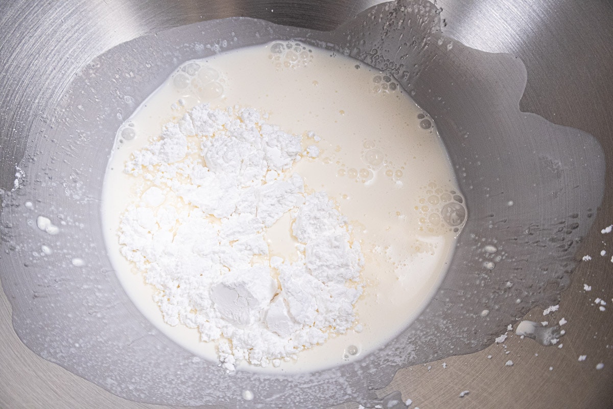 Heavy cream and powdered sugar in the bowl of a mixer.