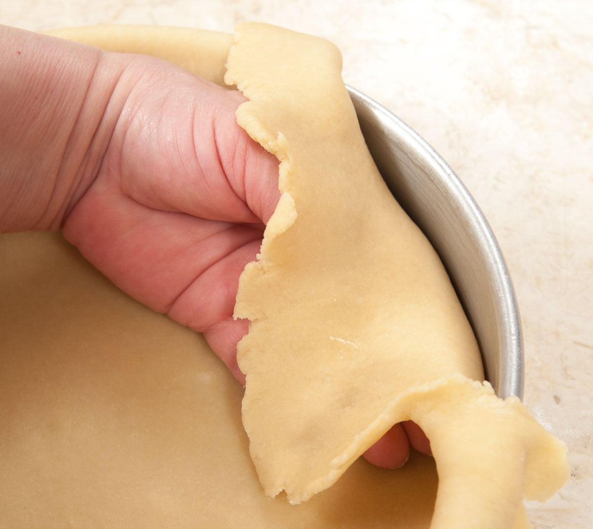 Fitting the dough into the edges of the pan ensuring a 90° angle.