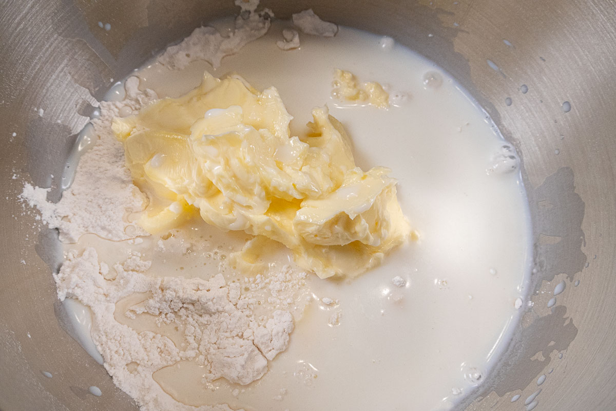 The butter and remaining milk are added to the dry ingredients in the mixing bowl.
