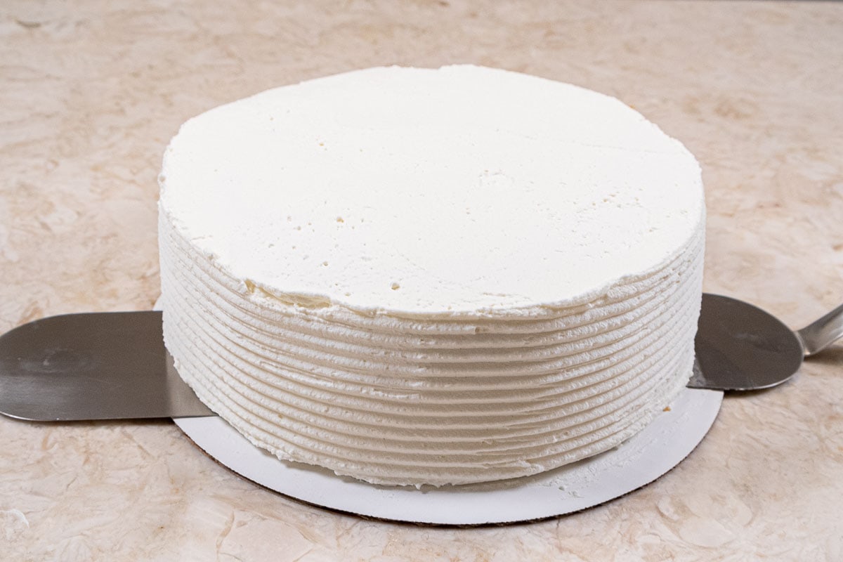 Two spatulas are placed, one on each side underneath the cake.