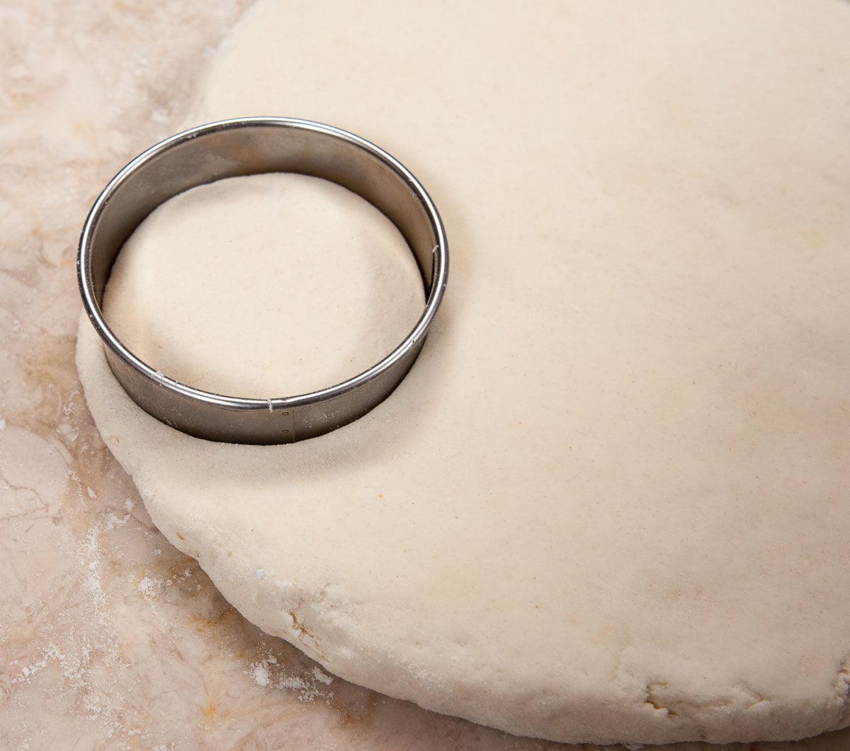The dough has been flattened to ½" and a cutter is in place.