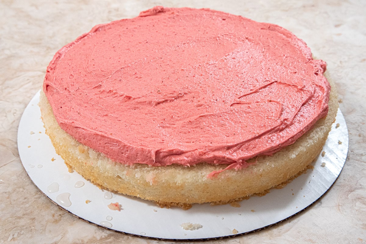 The Strawberry buttercream is spread on the bottom layer.