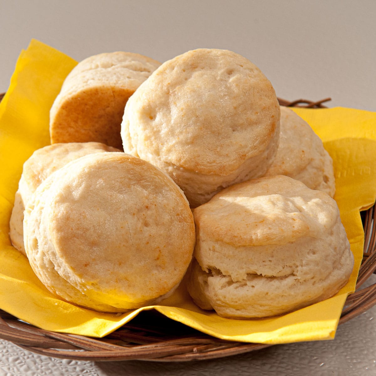 A basket of Cream Biscuits on a yellow napkin.