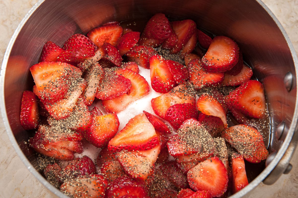 The strawberries, sugar, balsamic vinegar,  water, black pepper and water are placed in a sauce pan.