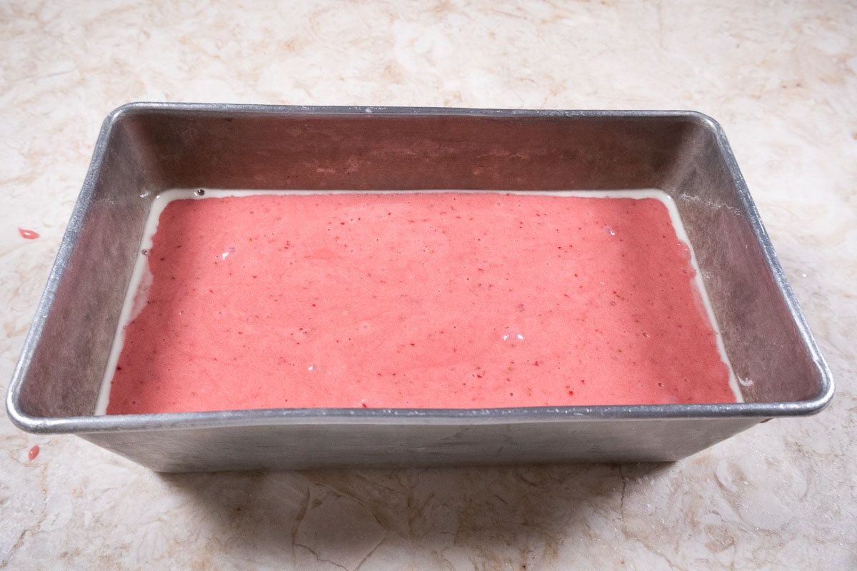 The strawberry bread batter has been poured into a loaf pan.