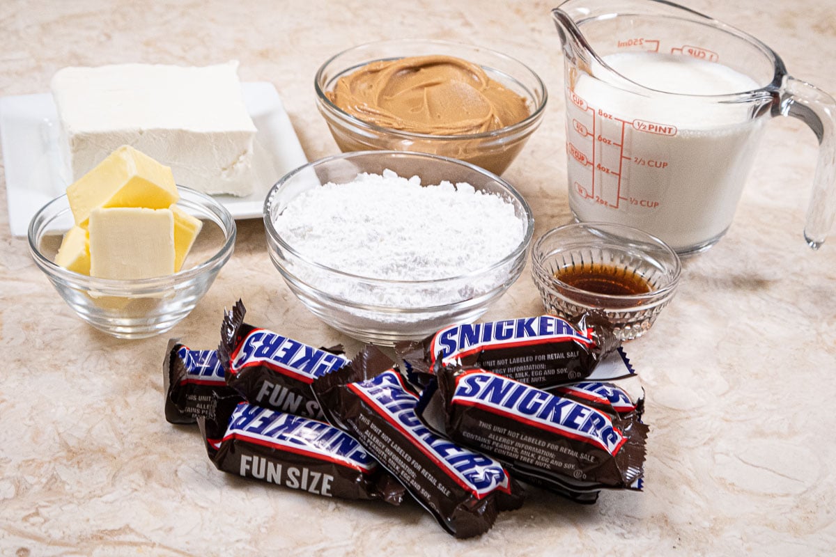 Ingredients for the peanut butter mousse are cream cheese, peanut butter, heavy cream, butter, powdered sugar, vanilla and snickers bars.