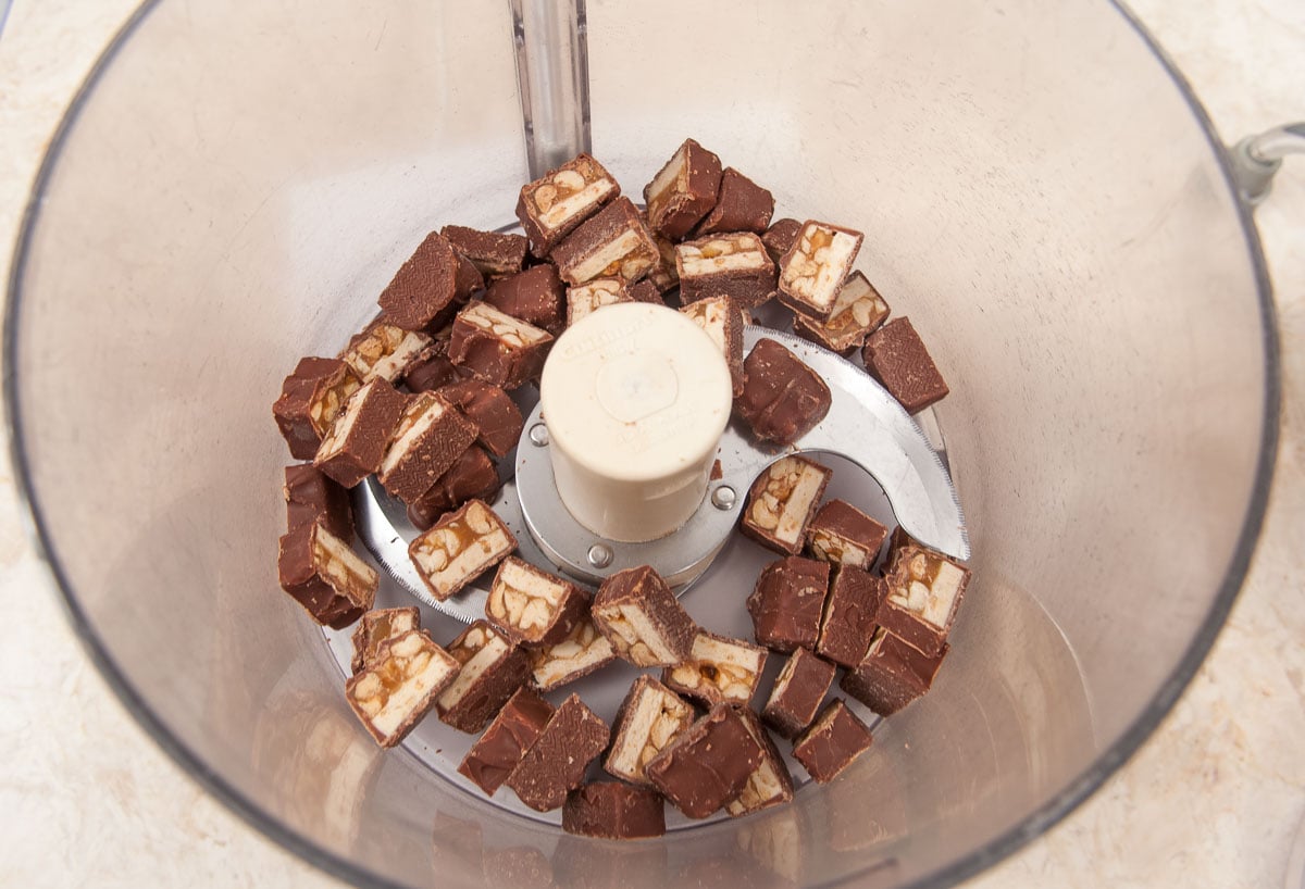 Cut Snickers are placed in the bowl of a processor