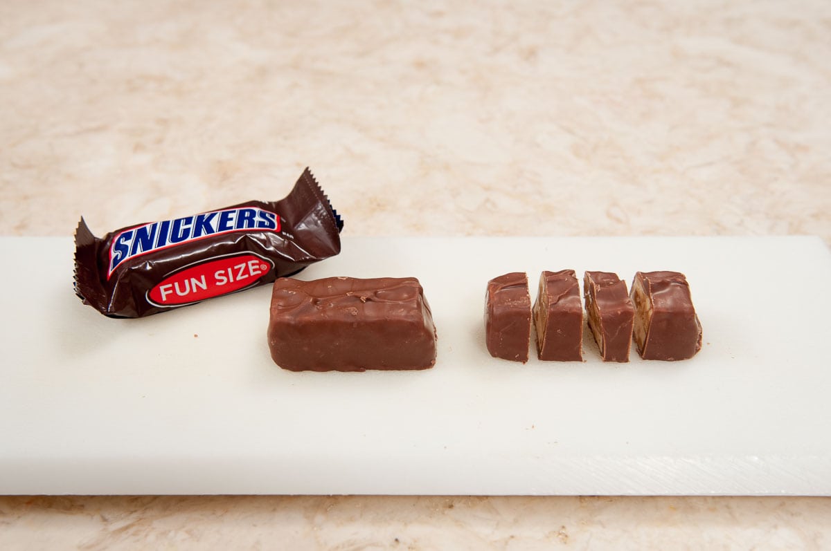 Fun size Snickers bars in package, out of package and cut into pieces.