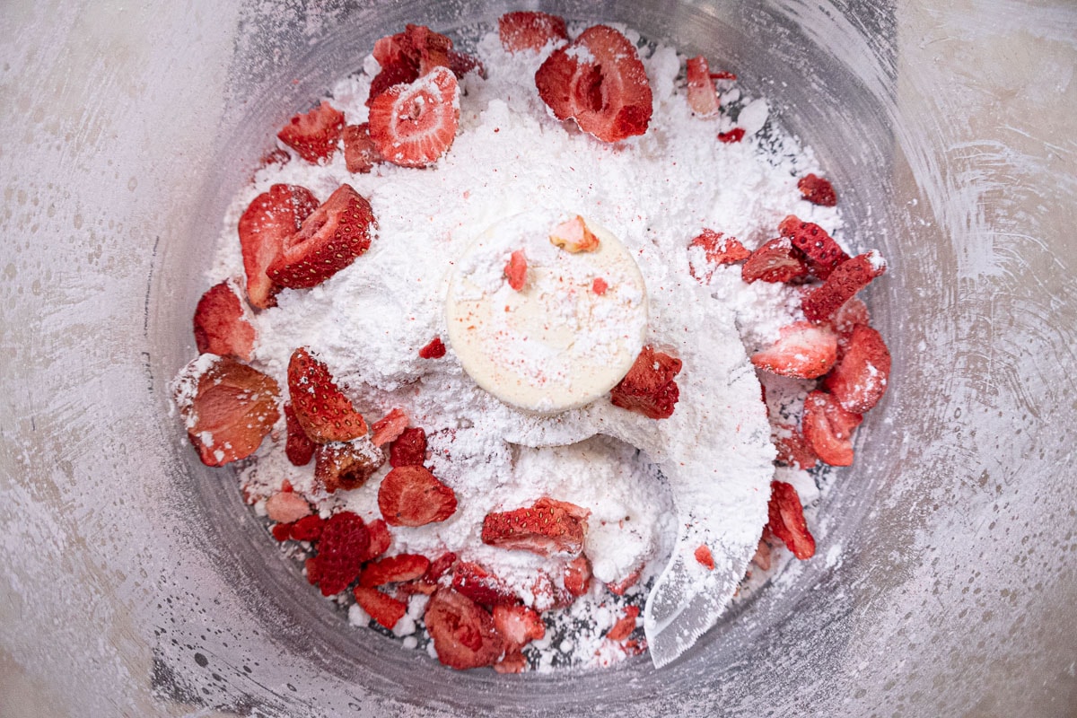Half of the strawberries and powdered sugar are placed in the processor bowl.