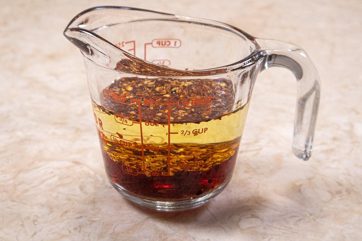 The vinegar, oil and red pepper flakes in a measuring cup.