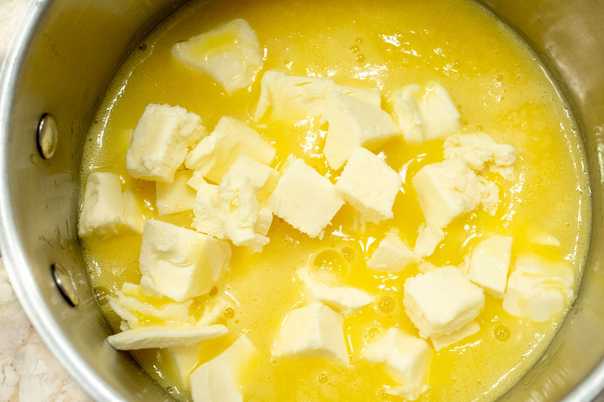 The cold butter is added to the lemon mixture in the pan.