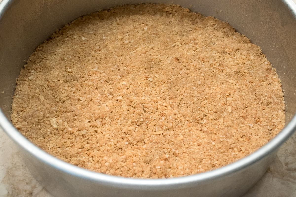 The crumb crust is pressed evenly in the pan.