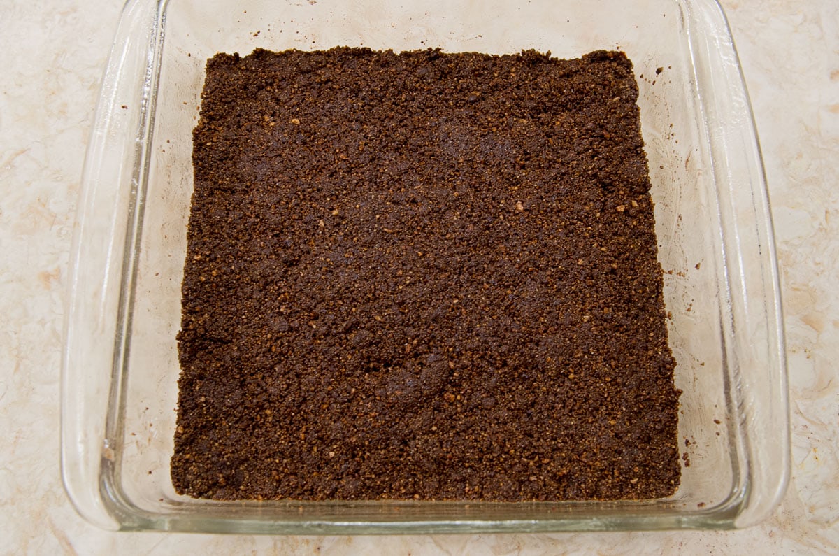 The crumbs have been pressed into a square baking dish.