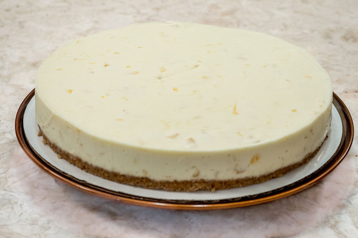 Finished cheesecake on a round plate edged in gold.