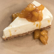 A slice of Pina Colada cheesecake with caramelized pineapple sits on a tan plate.