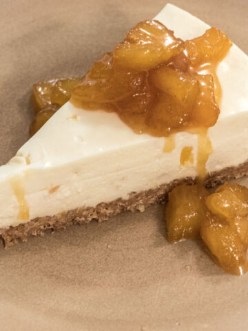 A slice of Pina Colada cheesecake with caramelized pineapple sits on a tan plate.