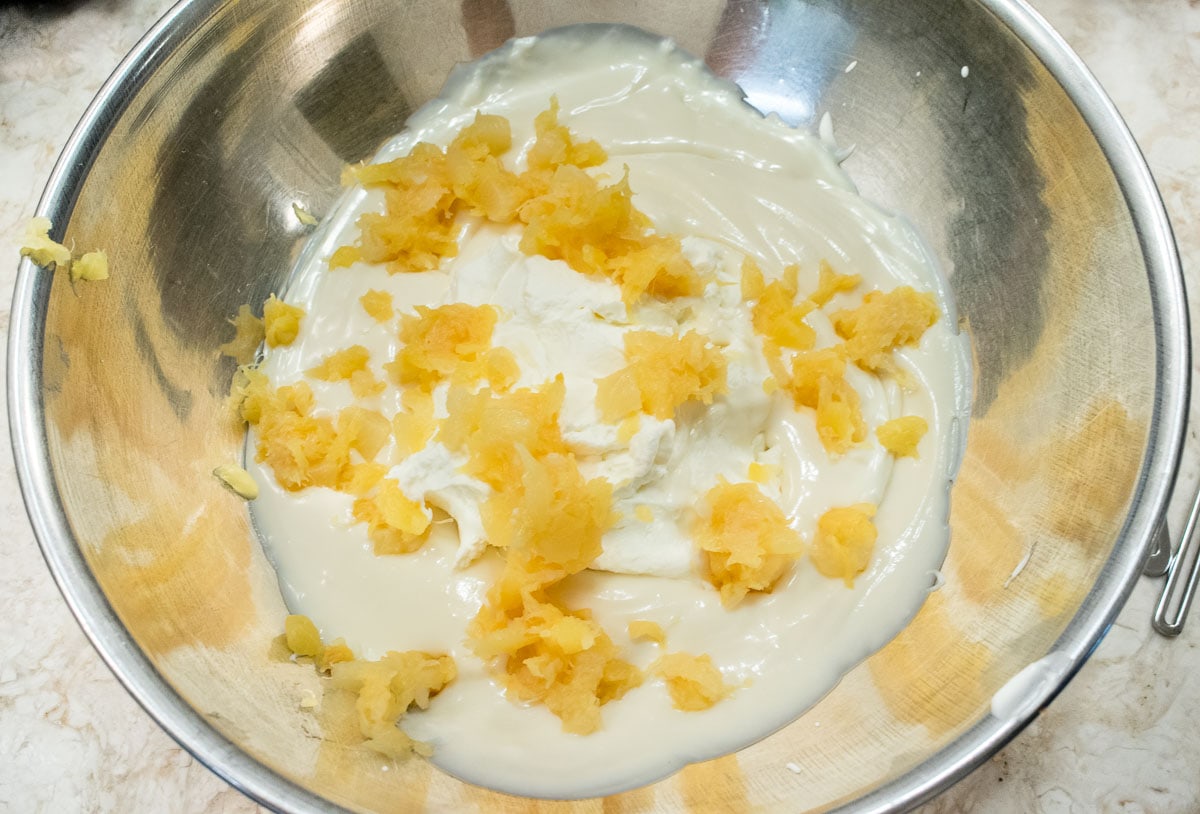 The pineapple is added to the filling and the whipped cream in a bowl.