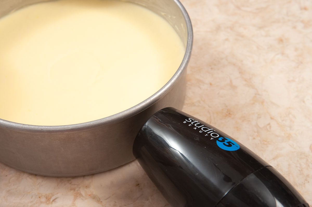 A blow dryer is held close to the pan to heat the mousse so it can be released smoothly from the pan.