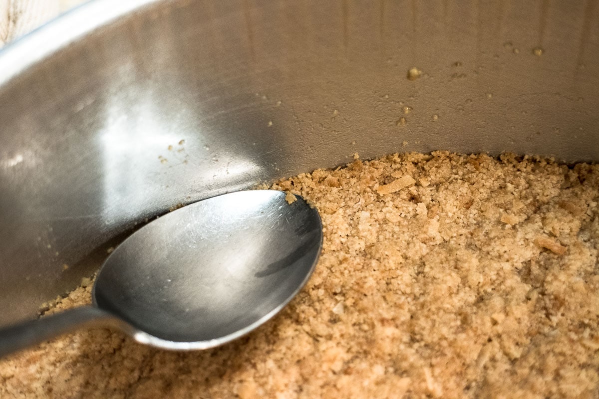 A spoon is used to seal the crust back to the edge of the pan after baking.