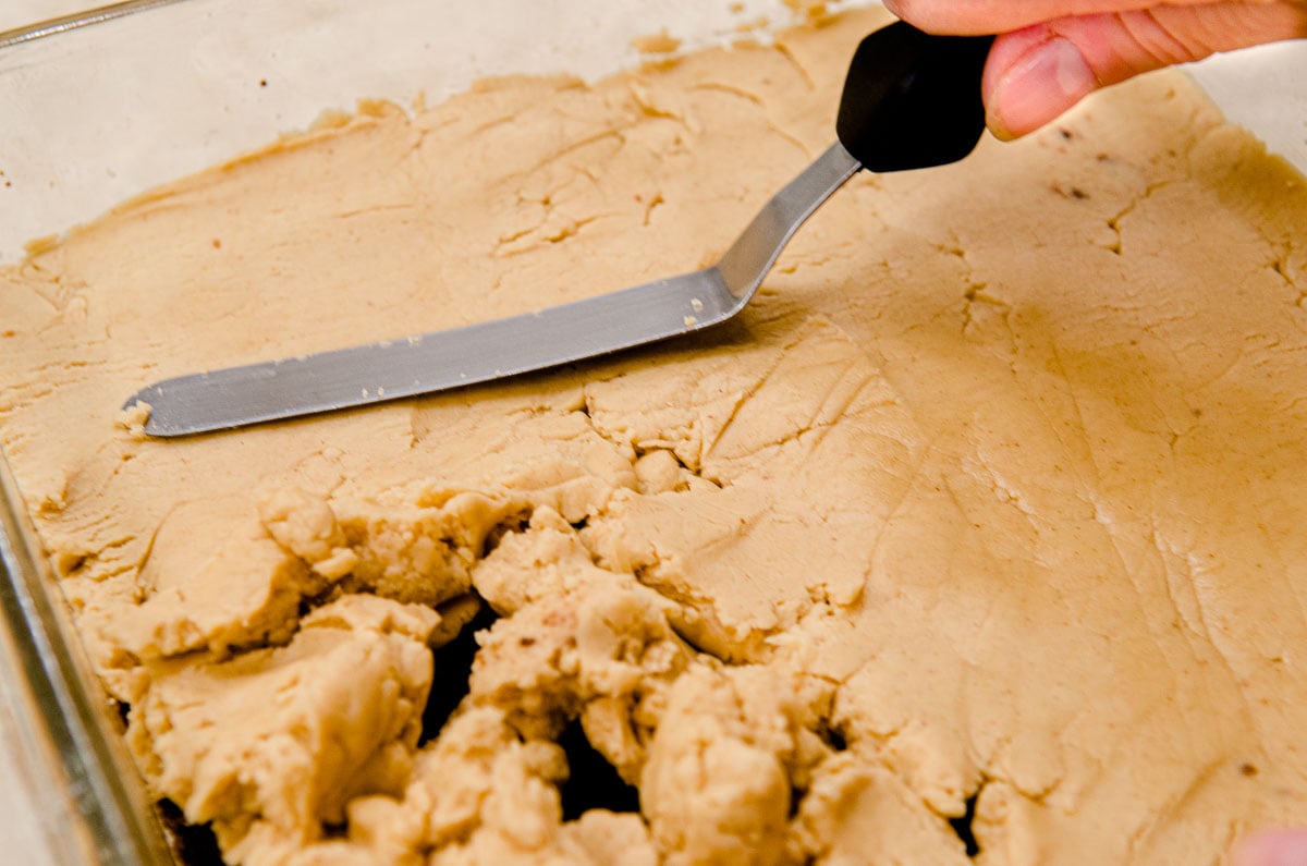 The filling is spread over the crust with a small offset spatula.