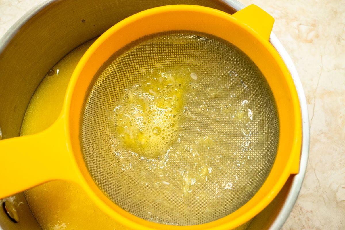 The mixture is strained into the top of a double boiler to remove  any lumps.