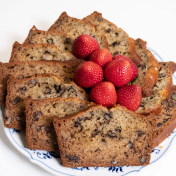 Slices of Banana Bread in a circle with strawberries in the middle on a blue and white plate.