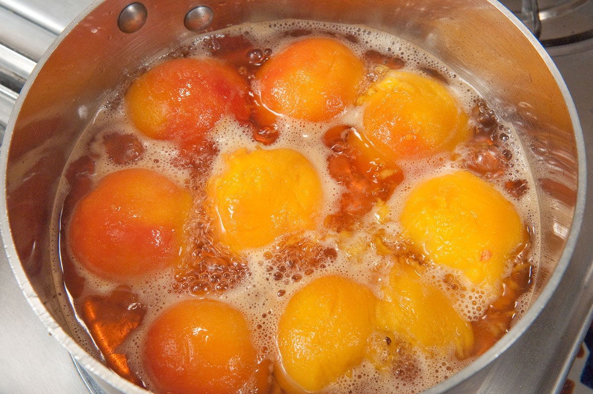 The poaching syrup is brought to a rolling boil and the peaches are placed in it cut side down.