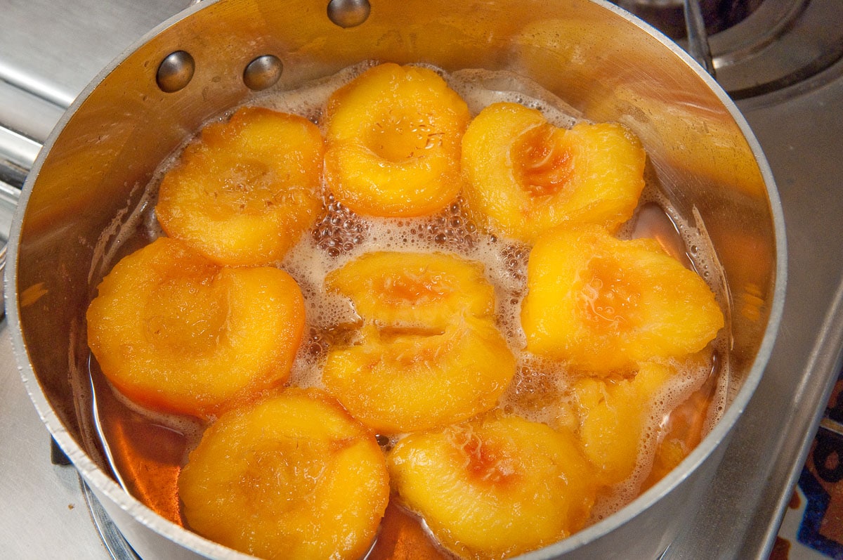 The peaches are turned cut side up in the liquid.