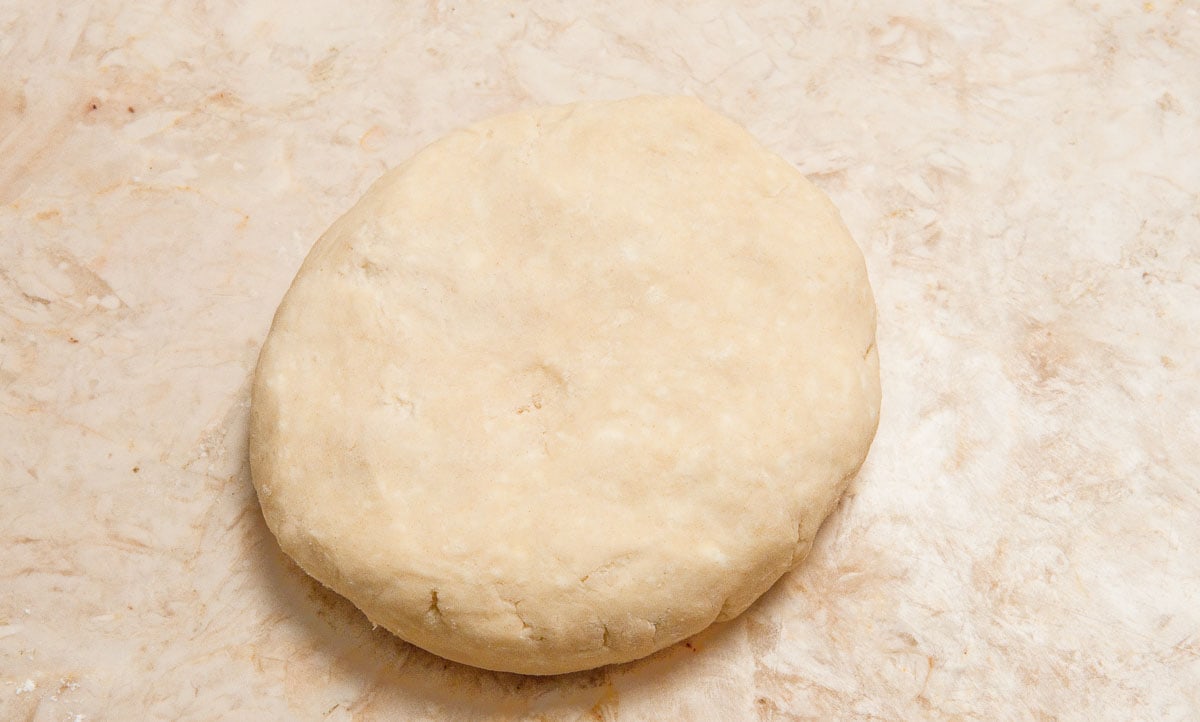 The clumps of dough are pushed together and  shaped into a smooth flat round.