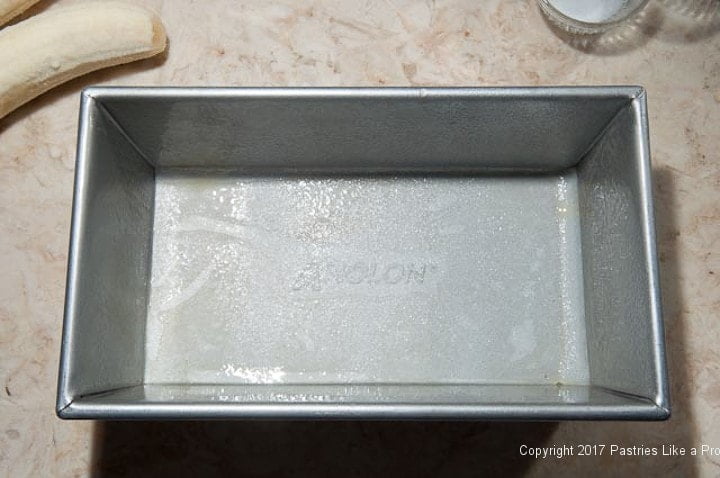 The loaf pan is prepared by lining it with parchment paper and spray the paper and the pan