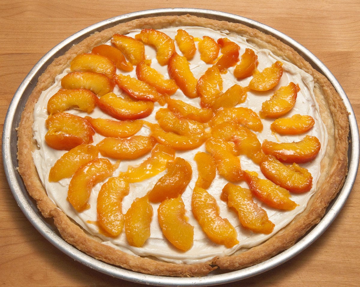 The peaches are sliced and arranged over the filling.