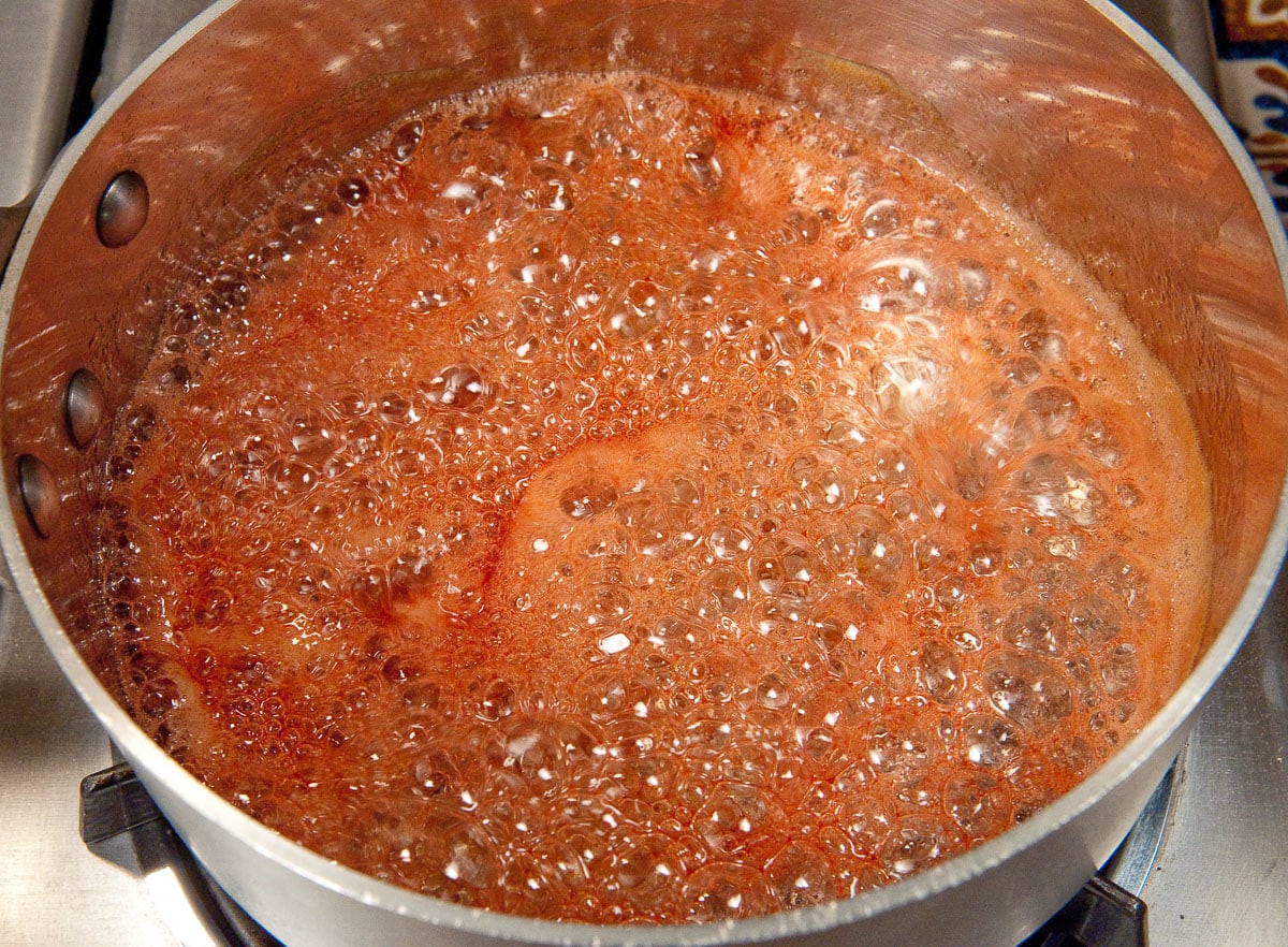 The poaching syrup is brought to a hard boil to reduce it.