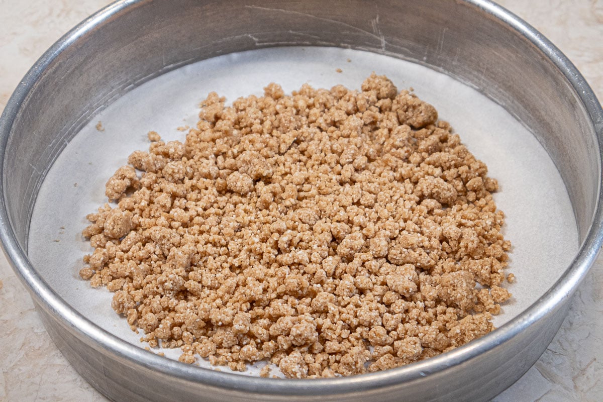 Unbaked crumb topping is placed in a pan lined with parchment paper.