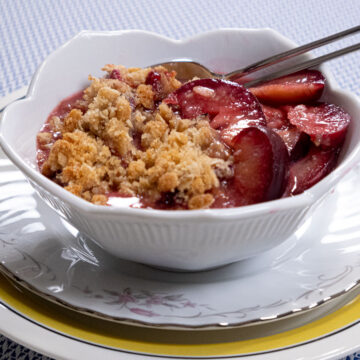 Plum Crisp ready to eat with a spoon in a white bowl.