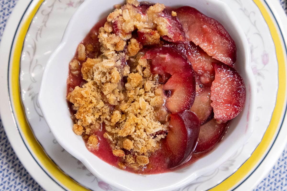 An overhead photo of the finished plum crisp with plums on the right side of the dish and crisp on the left.